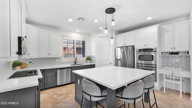 kitchen with appliances with stainless steel finishes, a sink, visible vents, and white cabinetry