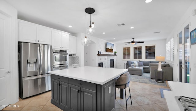 kitchen with visible vents, a kitchen island, appliances with stainless steel finishes, a fireplace, and white cabinetry