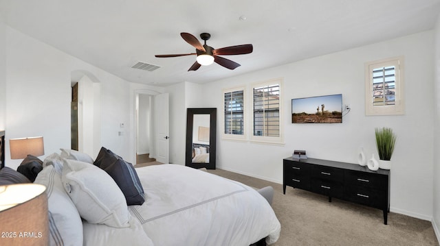 bedroom with light carpet, multiple windows, visible vents, and arched walkways