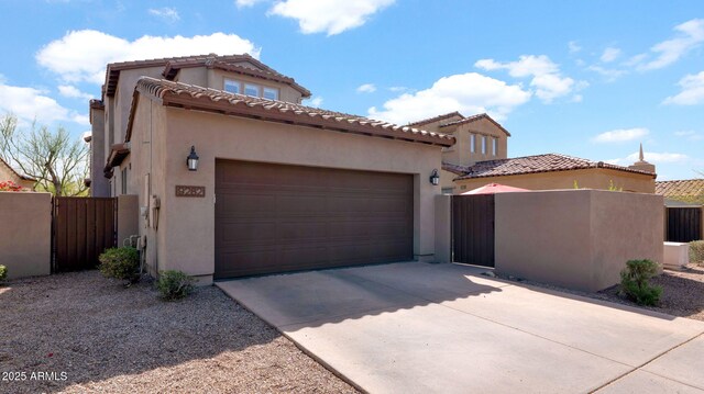 view of front facade with a garage, concrete driveway, a gate, and stucco siding