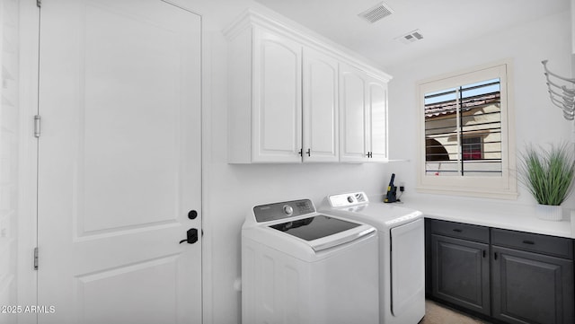 laundry room with visible vents, separate washer and dryer, and cabinet space