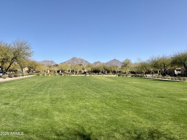 view of home's community with a rural view, a lawn, and a mountain view