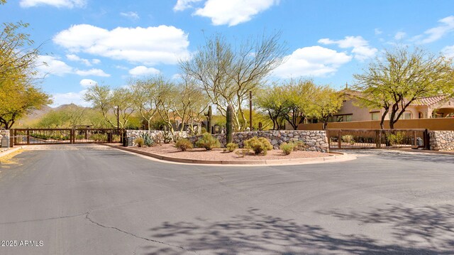 view of road with a gate, curbs, and a gated entry