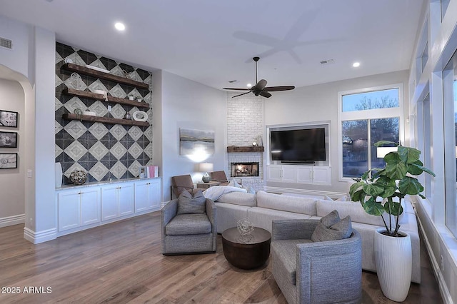 living room featuring ceiling fan, hardwood / wood-style floors, and a fireplace