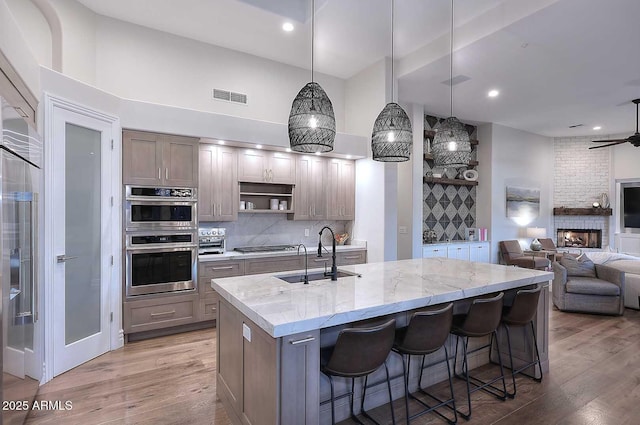 kitchen featuring light stone countertops, sink, pendant lighting, a breakfast bar, and a center island with sink