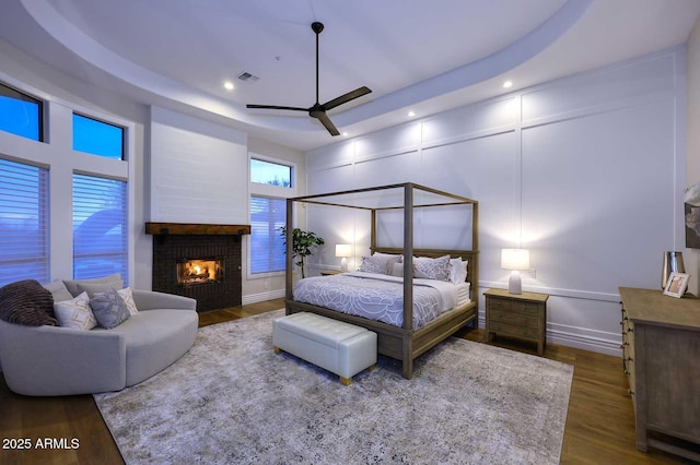 bedroom with ceiling fan, hardwood / wood-style floors, and a tray ceiling