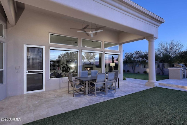 patio terrace at dusk featuring a yard and ceiling fan