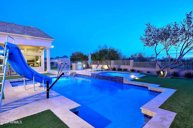 pool at dusk with an in ground hot tub, a water slide, a lawn, and a patio