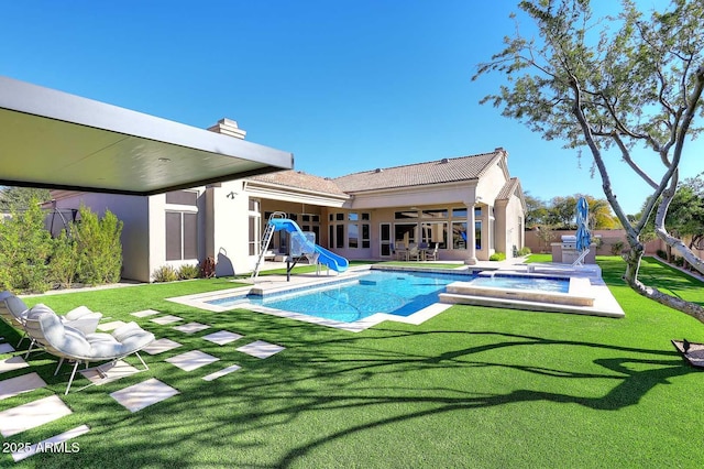 rear view of property with a swimming pool with hot tub, a yard, and a patio