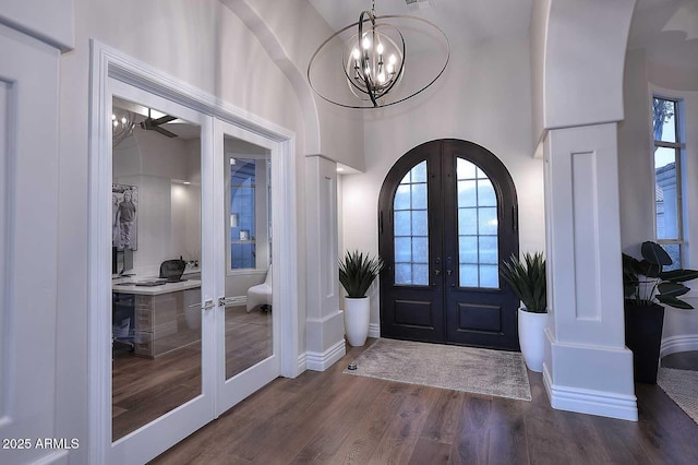 foyer featuring a towering ceiling, french doors, a wealth of natural light, and dark hardwood / wood-style floors