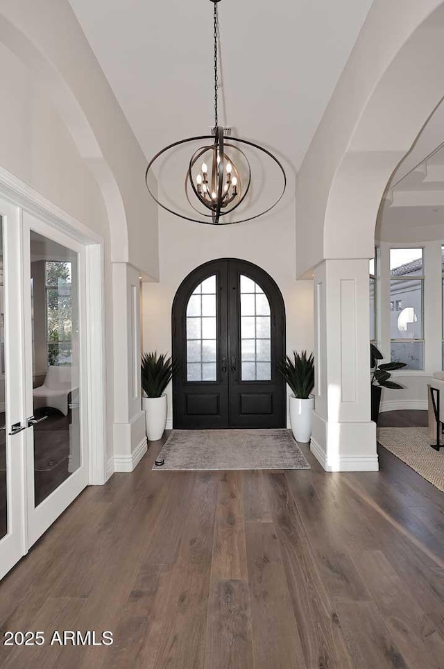 entryway with dark hardwood / wood-style flooring, a notable chandelier, and french doors