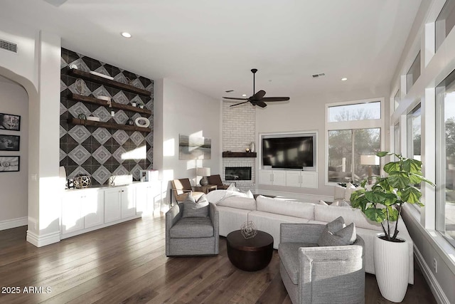 living room featuring ceiling fan, dark wood-type flooring, and a fireplace