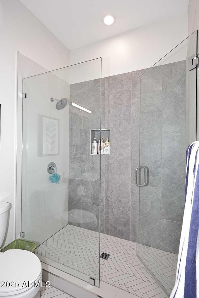 bathroom with a shower with shower door and toilet