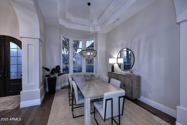 dining area featuring a tray ceiling, dark hardwood / wood-style floors, and a chandelier