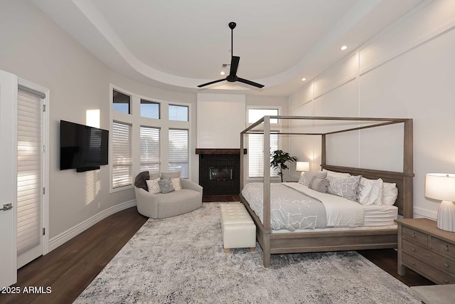 bedroom featuring ceiling fan, dark hardwood / wood-style floors, and a brick fireplace