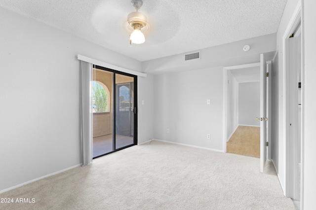 carpeted spare room featuring ceiling fan and a textured ceiling