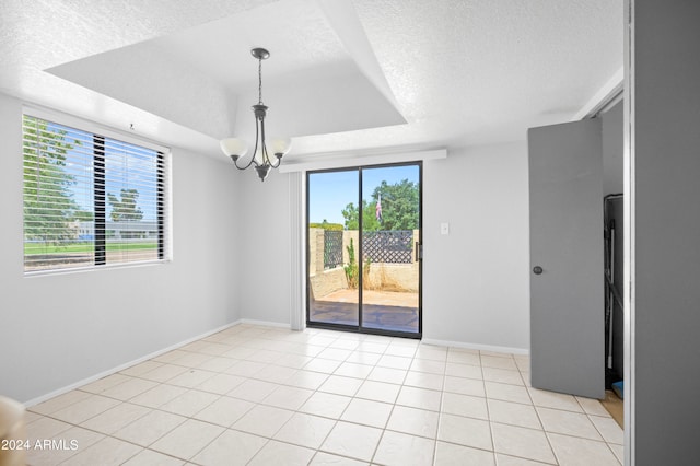 spare room featuring light tile patterned floors, plenty of natural light, an inviting chandelier, and a textured ceiling