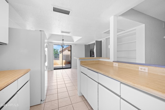 kitchen with white cabinets, white fridge, light tile patterned flooring, and a textured ceiling