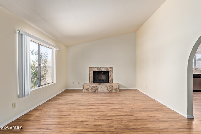 2164 S Estrella Cir, Mesa, AZ 85202 - unfurnished living room featuring light wood finished floors, a fireplace, and arched walkways