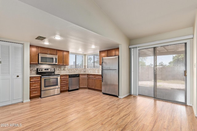 2164 S Estrella Cir, Mesa, AZ 85202 - kitchen with appliances with stainless steel finishes, brown cabinetry, light wood-type flooring, tasteful backsplash, and light countertops