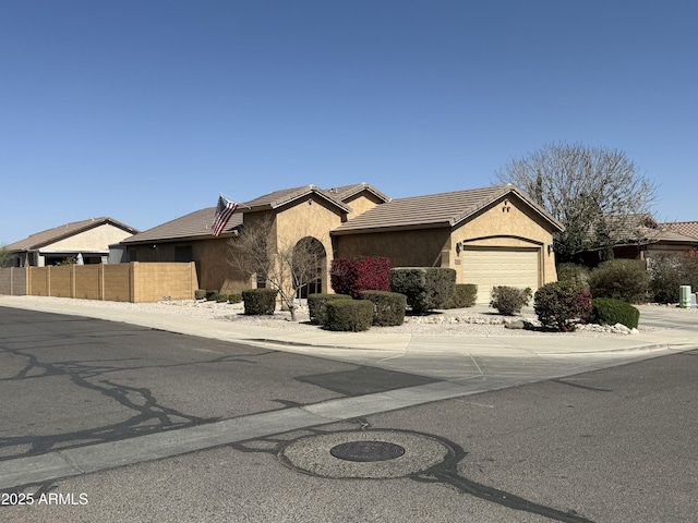 view of front of home with driveway, fence, a garage, a tile roof, and stucco siding