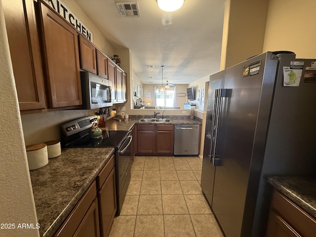 kitchen featuring light tile patterned floors, a sink, visible vents, a peninsula, and appliances with stainless steel finishes
