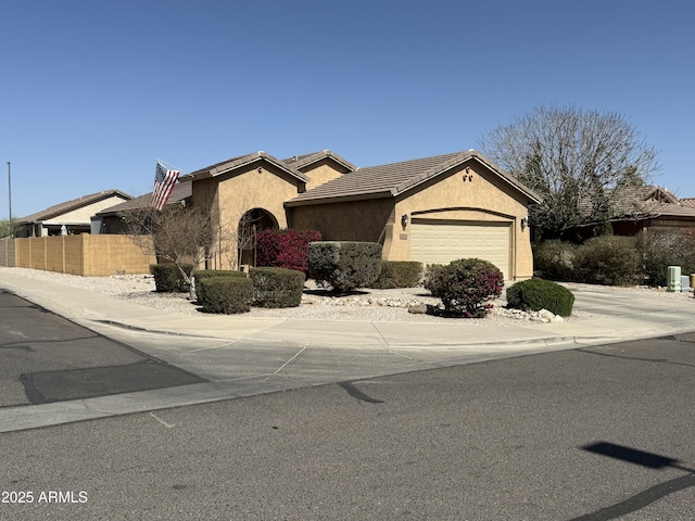 view of front facade featuring a tile roof, driveway, stucco siding, an attached garage, and fence