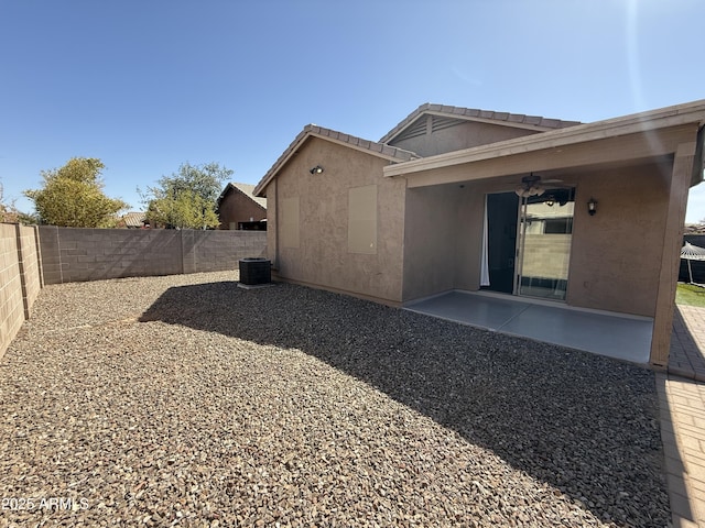 back of property with central air condition unit, a fenced backyard, a ceiling fan, stucco siding, and a patio area