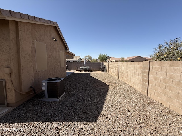 view of yard with a fenced backyard, central air condition unit, and a patio