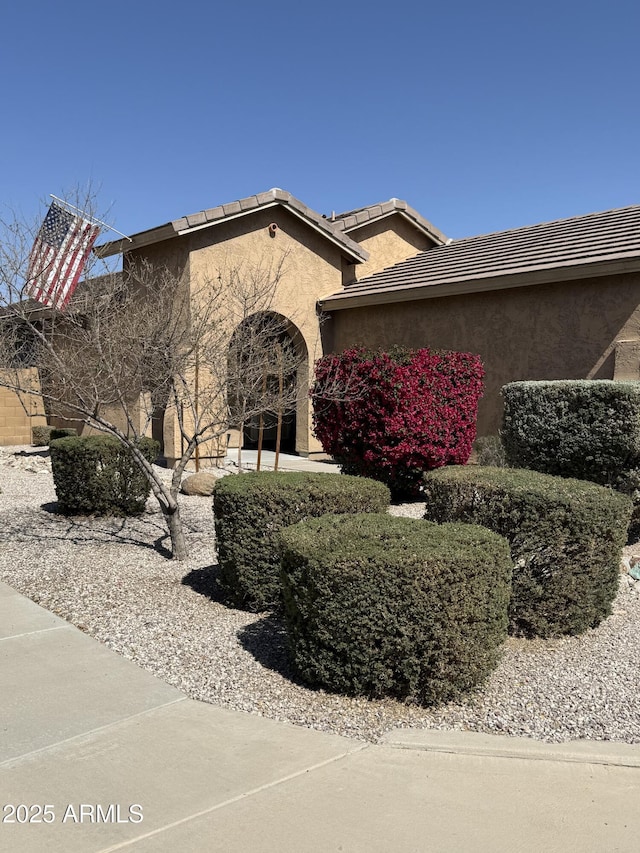 view of property exterior with a tile roof and stucco siding
