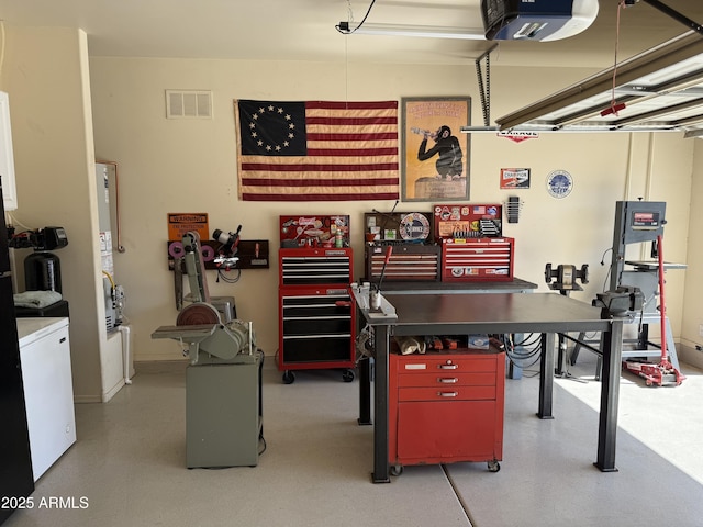 garage featuring a workshop area, washer / dryer, a garage door opener, and visible vents