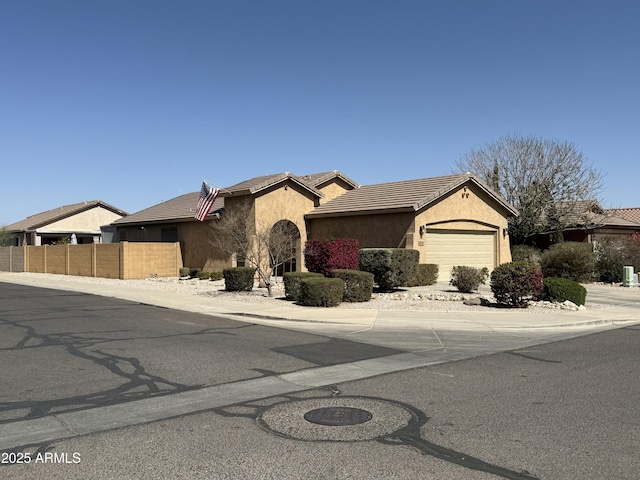 view of front of home with a tiled roof, stucco siding, fence, and an attached garage
