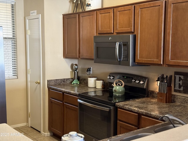 kitchen featuring stainless steel microwave, plenty of natural light, electric range oven, and brown cabinets