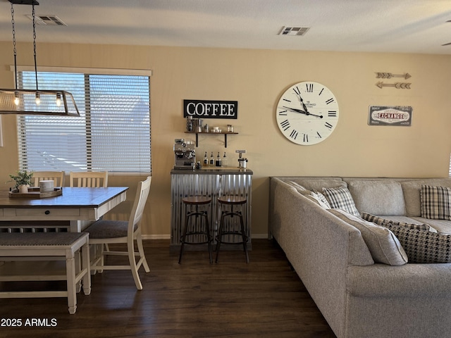 living area featuring baseboards, a dry bar, visible vents, and wood finished floors