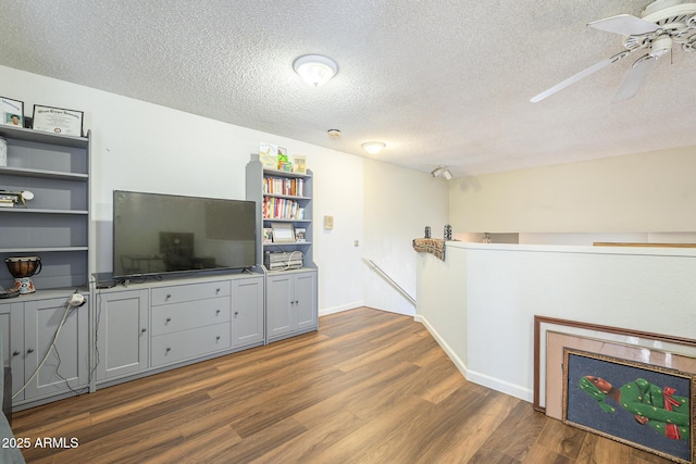 unfurnished living room featuring ceiling fan, dark hardwood / wood-style flooring, and a textured ceiling