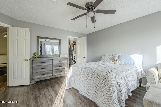 bedroom featuring ceiling fan, dark wood-type flooring, a textured ceiling, a walk in closet, and a closet