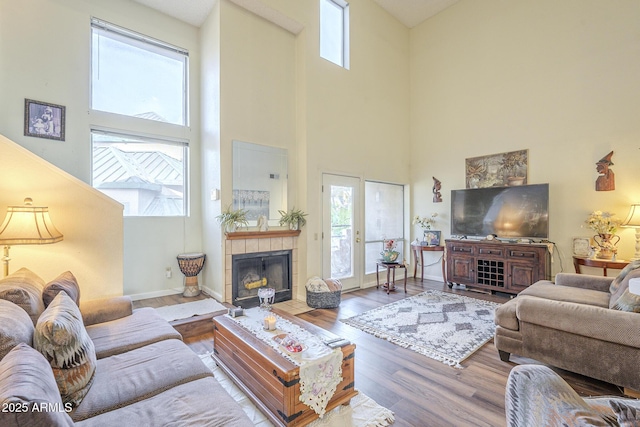 living room with a tiled fireplace, hardwood / wood-style floors, and a high ceiling