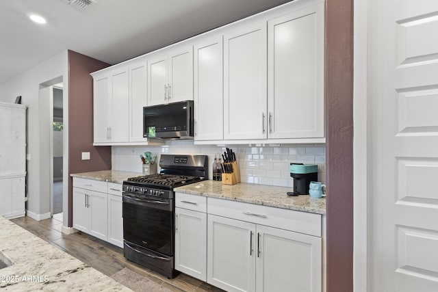 10165 E Gamma Ave, Mesa, AZ 85212 - kitchen with black range with gas stovetop, decorative backsplash, white cabinetry, light stone countertops, and light wood finished floors