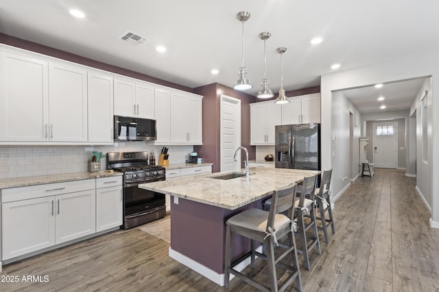 10165 E Gamma Ave, Mesa, AZ 85212 - kitchen with stainless steel range with gas stovetop, fridge with ice dispenser, a kitchen breakfast bar, decorative backsplash, and wood finished floors