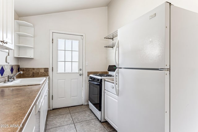 kitchen featuring sink, white cabinetry, light tile patterned floors, range with gas stovetop, and white fridge