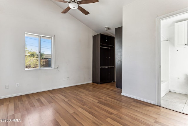 spare room featuring ceiling fan, light wood-type flooring, and lofted ceiling