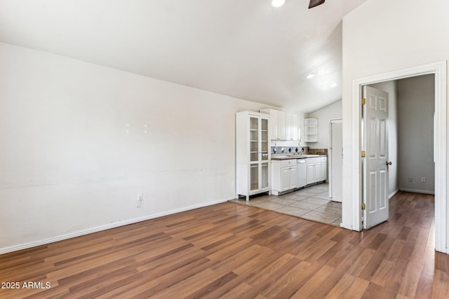 unfurnished living room with sink, light hardwood / wood-style floors, and lofted ceiling