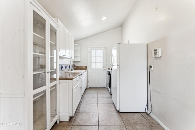 kitchen with vaulted ceiling, sink, white refrigerator, white cabinets, and stove