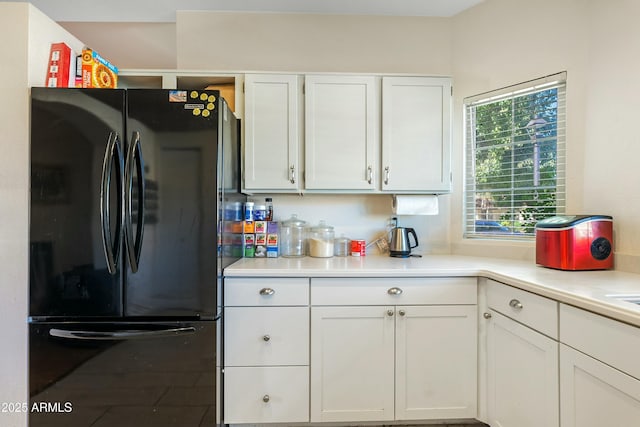 kitchen featuring white cabinetry and black fridge