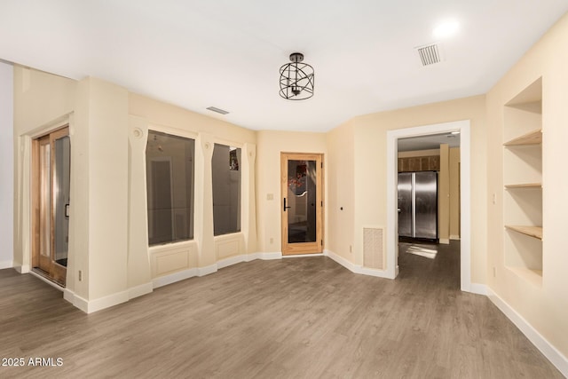 empty room with built in features and light wood-type flooring