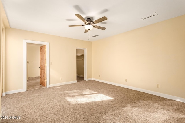 unfurnished bedroom featuring ceiling fan, a spacious closet, a closet, and carpet floors