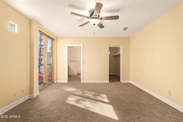 unfurnished bedroom with a closet, ceiling fan, carpet, and a spacious closet