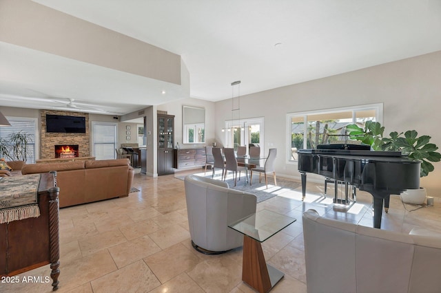 living room with a stone fireplace and ceiling fan