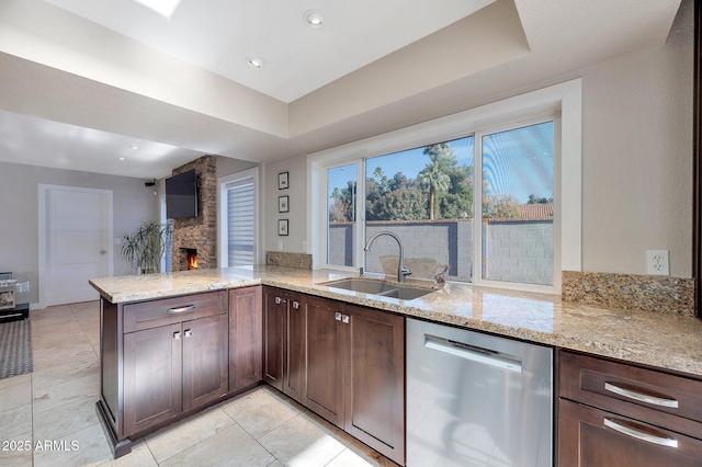 kitchen featuring sink, stainless steel dishwasher, kitchen peninsula, and light stone countertops