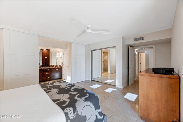 bedroom with ensuite bath, light tile patterned floors, ceiling fan, and a closet